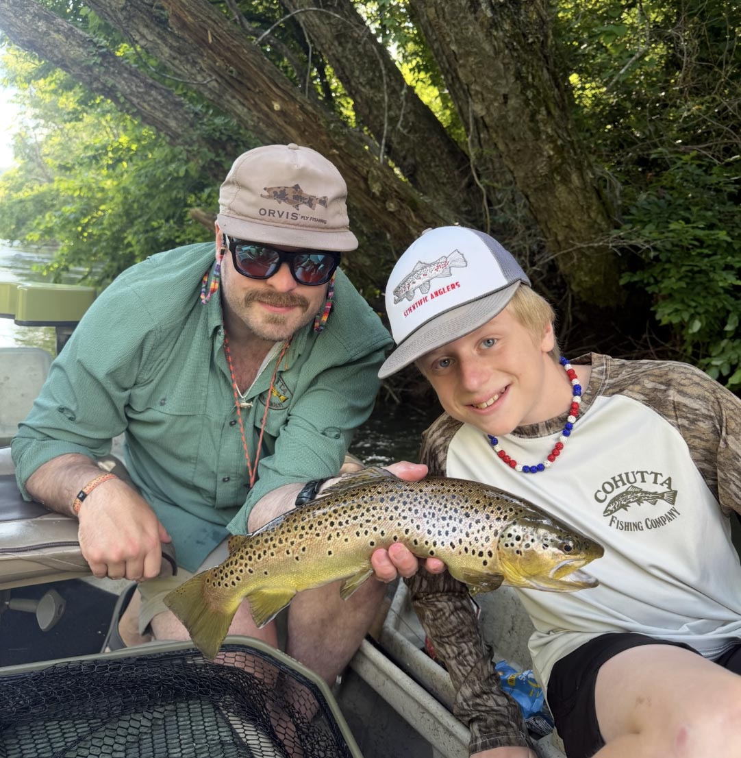 Young angler holding a brown trout during a guided fly fishing trip in Blue Ridge, Georgia